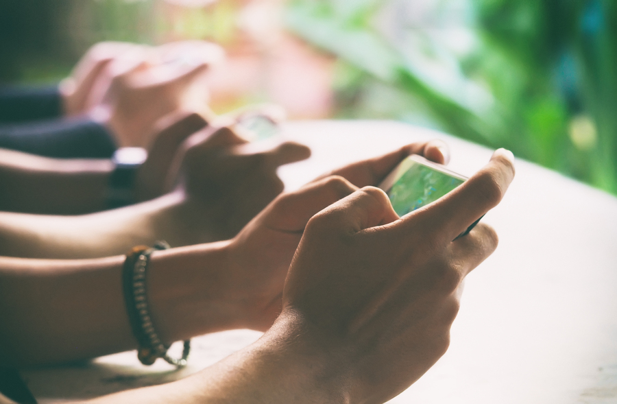 How to Host Your Own Snake.io Tournament with Friends 1 People using their smart phones, playing a game with blurred focus and vintage color background